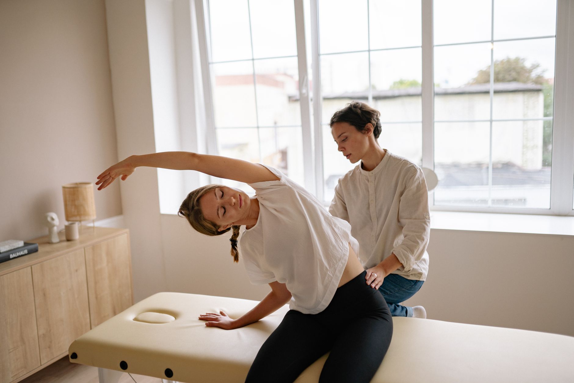 A woman receives a therapeutic massage and stretching on a massage table indoors, physical therapy near me five points